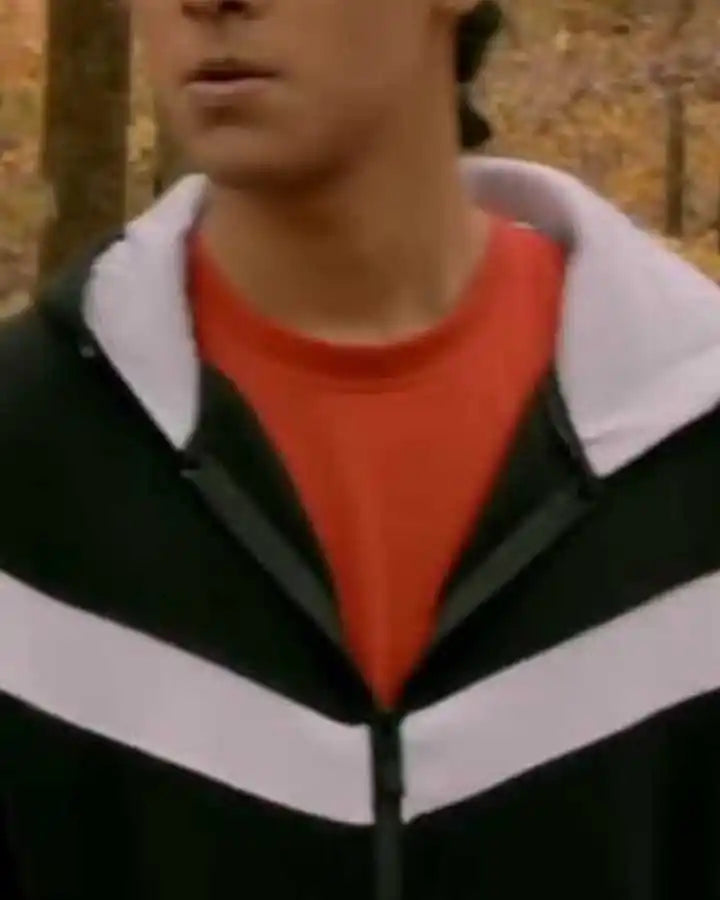Person wearing a black and white jacket with a red shirt underneath, standing in an outdoor setting with trees.